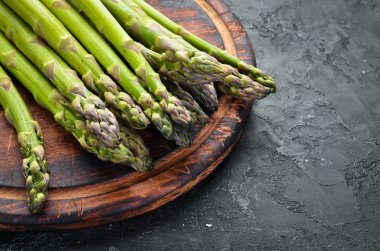 siyah bir arka plan üzerinde taze yeşil kuşkonmaz demetleri. Sağlıklı yiyecekler. Üst te. Metniniz için boş alan.