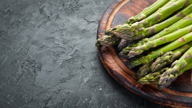 siyah bir arka plan üzerinde taze yeşil kuşkonmaz demetleri. Sağlıklı yiyecekler. Üst te. Metniniz için boş alan.