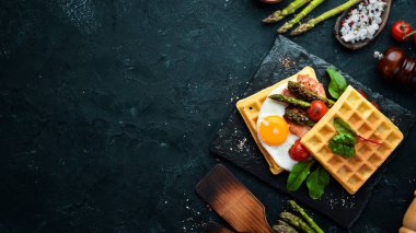 Kahvaltı. Yumurta, kuşkonmaz ve pastırma ile Belçika waffle. Sağlıklı yiyecekler. Üst te. Metniniz için boş alan.