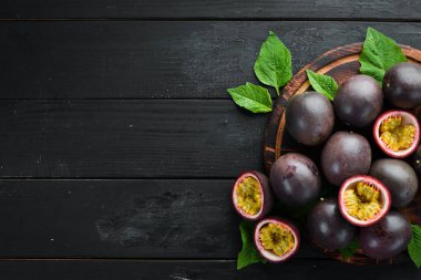 Siyah bir arka plan üzerinde yaprakları ile Passion meyve. Tropikal Meyveler. Üst te. Metin için boş alan.