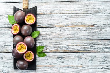 Beyaz ahşap arka plan üzerinde bir yaprak ile Passion meyve. Tropikal Meyveler. Üst te. Metin için boş alan.