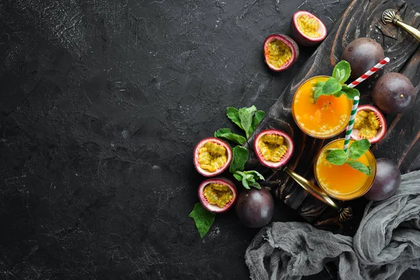 Passion fruits juice and fruit on a black background. Tropical Fruits. Top view. Free space for text.