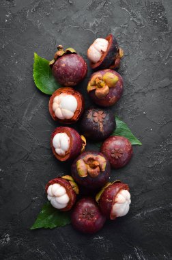Mangosteen with a leaf on a black stone background. Tropical Fruits. Top view. Free space for text. clipart