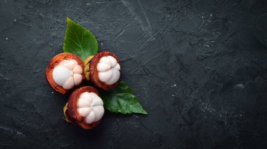Siyah taş arka plan üzerinde bir yaprak ile Mangosteen. Tropikal Meyveler. Üst te. Metin için boş alan.