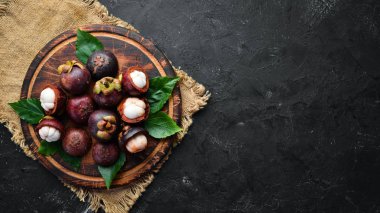 Siyah taş arka plan üzerinde bir yaprak ile Mangosteen. Tropikal Meyveler. Üst te. Metin için boş alan.