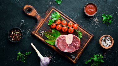 Siyah bir arka plan üzerinde baharat ve otlar ile Osso Buco yapmak için Ham taze çapraz kesilmiş dana sapı. Üst te. Metniniz için boş alan.