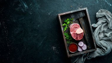 Siyah bir arka plan üzerinde baharat ve otlar ile Osso Buco yapmak için Ham taze çapraz kesilmiş dana sapı. Üst te. Metniniz için boş alan.