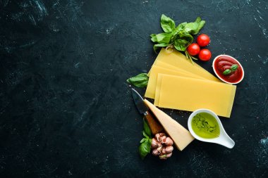 Lazanya ham yaprak ve diğer malzemeler. Siyah bir arka plan üzerinde. Üst te. Metniniz için boş alan.