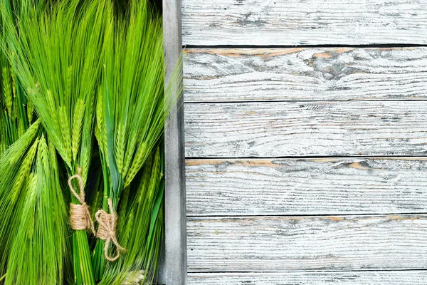 Green rye in a wooden box. On a wooden background. Top view. Free space for your text.