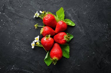 Siyah taş arka plan üzerinde yaprakları ile taze çilek. Çilek Üst görünüm. Metniniz için boş alan.