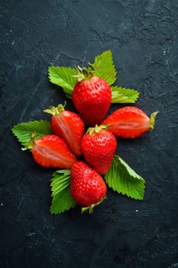 Siyah taş arka plan üzerinde yaprakları ile taze çilek. Çilek Üst görünüm. Metniniz için boş alan.