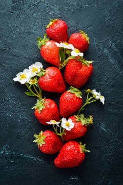 Siyah taş arka plan üzerinde yaprakları ile taze çilek. Çilek Üst görünüm. Metniniz için boş alan.