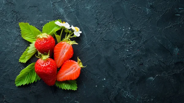 Siyah taş arka plan üzerinde yaprakları ile taze çilek. Çilek Üst görünüm. Metniniz için boş alan.