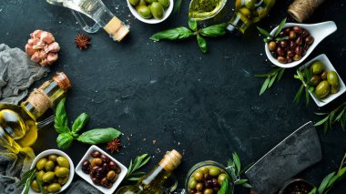 Zeytinyağı, zeytin ve baharatlar siyah taş zemin üzerinde. Üst te. Metniniz için boş alan.