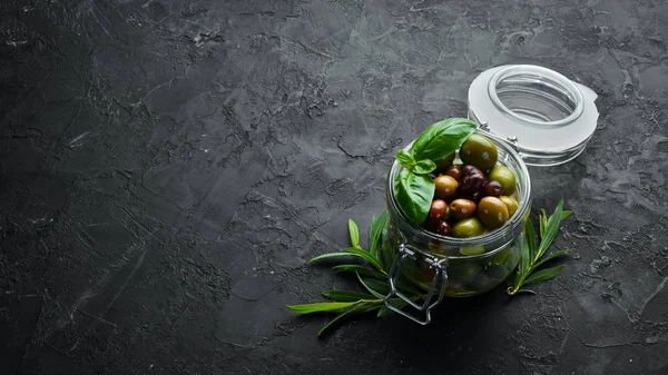 Olives A set of colored olives on a black stone background. Top view. Free space for your text.