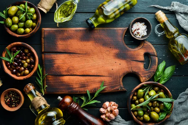 Olive oil and olives on a black wooden background.