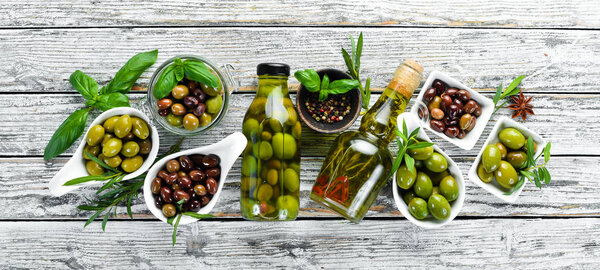 Olive oil and olives on a white wooden background. Top view. Free space for your text.