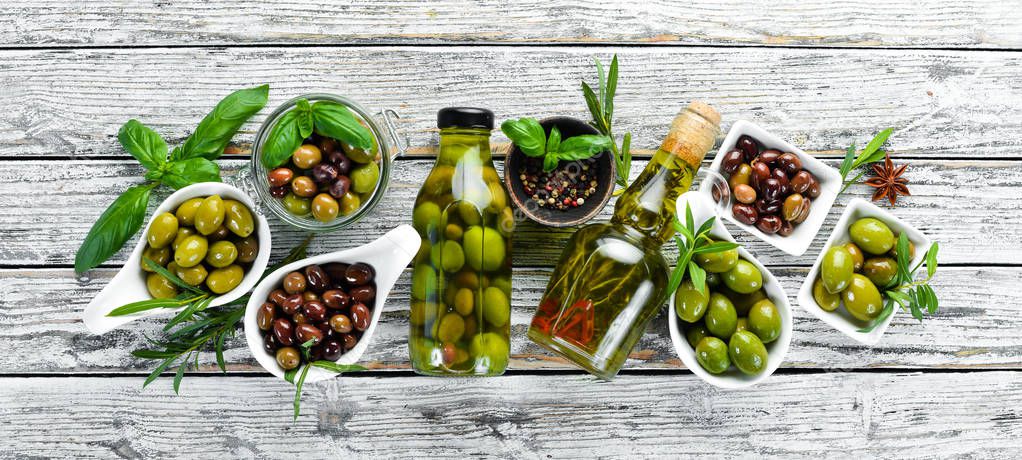 Olive oil and olives on a white wooden background. Top view. Free space for your text.