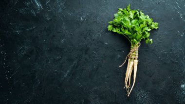 Kök maydanoz ve maydanoz siyah bir arka plan üzerinde. Üst te. Metniniz için boş alan.