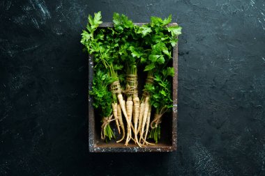 Kök maydanoz ve maydanoz siyah bir arka plan üzerinde. Üst te. Metniniz için boş alan.