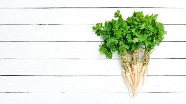 Beyaz ahşap arka plan üzerinde maydanoz kökü. Üst te. Metniniz için boş alan.