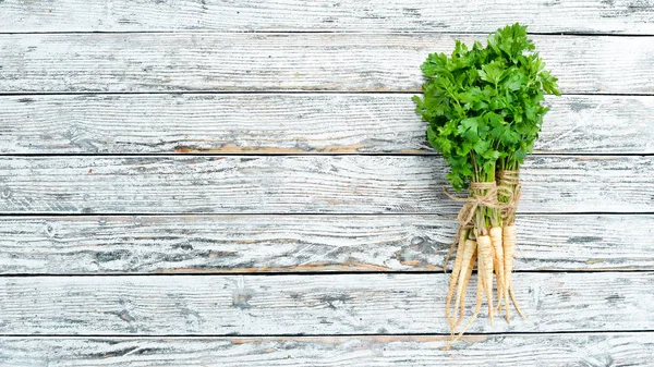 Parsley root on a white wooden background. Top view. Free space for your text.