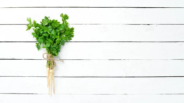 Parsley root on a white wooden background. Top view. Free space for your text.