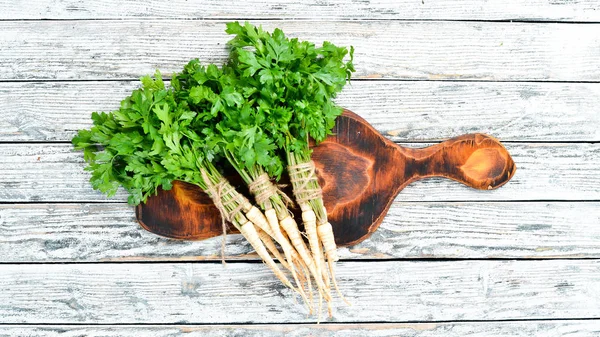 Parsley root on a white wooden background. Top view. Free space for your text.