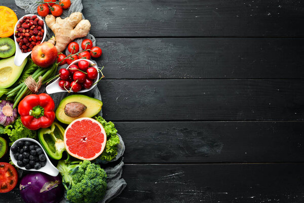 Fresh vegetables and fruits on a black background. Vitamins and minerals. Top view. Free space for your text.