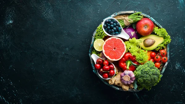 Fresh vegetables and fruits on a black background. Vitamins and minerals. Top view. Free space for your text.