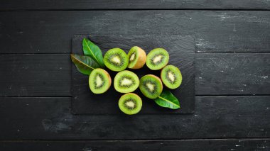 Taze kivi ve yeşil yapraklar masada. Rustik tarz. Meyve. Üst te. Metin için boş alan.
