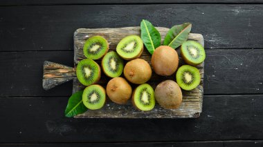Taze kivi ve yeşil yapraklar masada. Rustik tarz. Meyve. Üst te. Metin için boş alan.