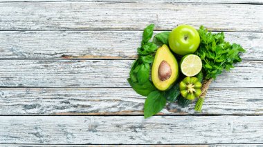 Taze organik yeşil meyveler ve sebzeler. Avokado, kivi, soğan, kireç, maydanoz. Organik yiyecekler. Rustik tarzda. Üst görünüm. Metin için boş alan.