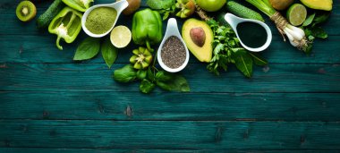 Sağlıklı Yeşil gıda. Meyve ve sebzeler - avokado, limon, soğan, elma, kivi, spirulina. Mavi ahşap bir arka plan üzerinde. Üst te. Metniniz için boş alan.