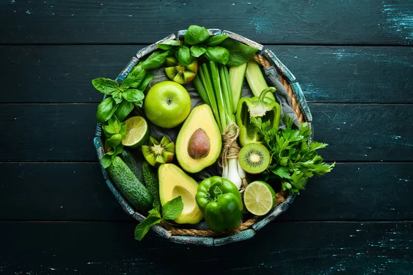 Fresh Green Fruits and Vegetables. Pure selection and source of vegetable protein on a wooden aged background. Avocados, grapes, cucumbers, kiwi, apples, lime, green pepper.