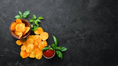 Siyah bir arka planda baharatlarla patates cipsi. Bira için aperatifler. Üst görünüm. Metin için boş alan.