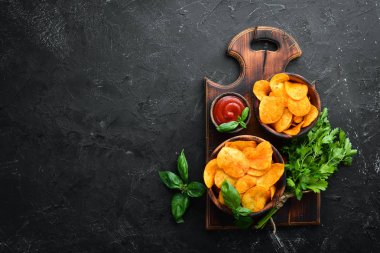 Siyah bir arka planda baharatlarla patates cipsi. Bira için aperatifler. Üst görünüm. Metin için boş alan.