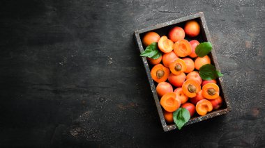 Bir kutuda yeşil yaprakları ile taze kayısı. Rustik tarz. Üst te. Metniniz için boş alan.