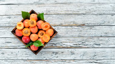 Bir kutuda yeşil yaprakları ile taze kayısı. Rustik tarz. Üst te. Metniniz için boş alan.