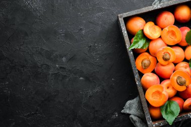 Siyah bir arka plan üzerinde yeşil yaprakları ile taze kayısı. Rustik tarz. Üst te. Metniniz için boş alan.