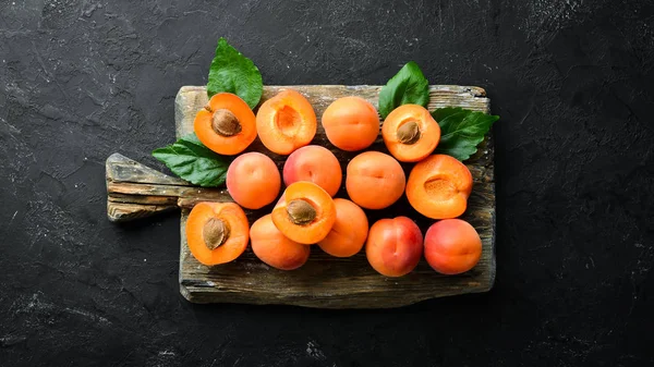 Siyah bir arka plan üzerinde yeşil yaprakları ile taze kayısı. Rustik tarz. Üst te. Metniniz için boş alan.