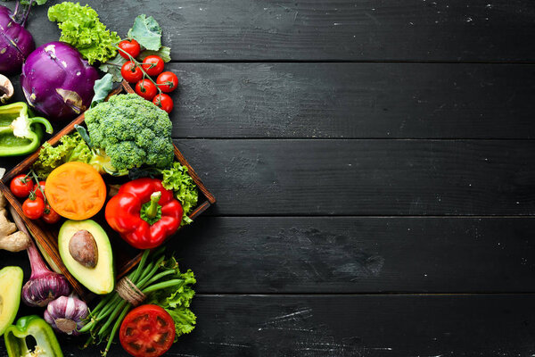 Fresh vegetables on a black background. Vegetarian food. Top view. Free space for your text.