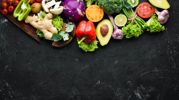 Fresh vegetables on a black background. Vegetarian food. Top view. Free space for your text.