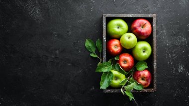 Siyah bir arka plan üzerinde yeşil yaprakları ile renkli elma. Meyve. Üst te. Metin için boş alan.
