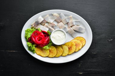 Fırında patatesli ringa balığı. Tabakta. Ahşap bir arka plan üzerinde. Üst te. Metniniz için boş alan.