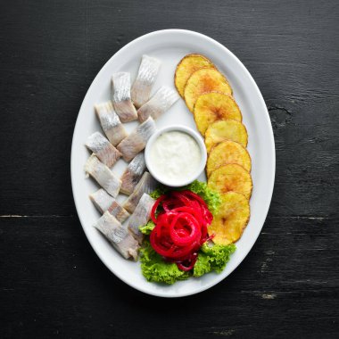 Fırında patatesli ringa balığı. Tabakta. Ahşap bir arka plan üzerinde. Üst te. Metniniz için boş alan.