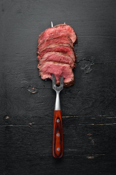 Rindersteak Auf Einer Gabel Auf Einem Hölzernen Hintergrund Ansicht Von — Stockfoto