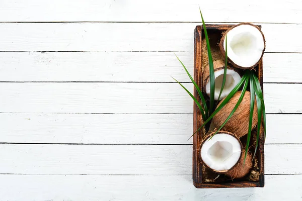 Tahta bir kutuda hindistan cevizi. Tropikal Meyveler. Somun. Üst te. Metniniz için boş alan.