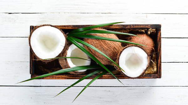 Coconut in a wooden box. Tropical Fruits. Nut. Top view. Free space for your text.