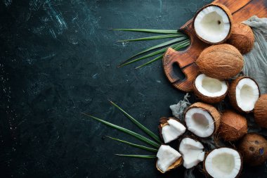 Hindistan cevizi palmiye yaprakları ile siyah bir taş arka plan üzerinde. Tropikal Meyveler. Somun. Üst te. Metniniz için boş alan.